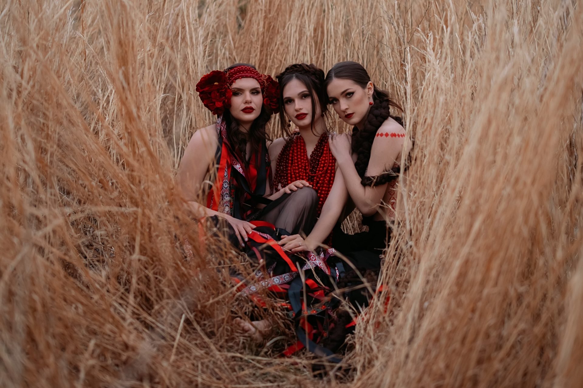 Three ladies in modern Ukrainian costumes on the field of rye.