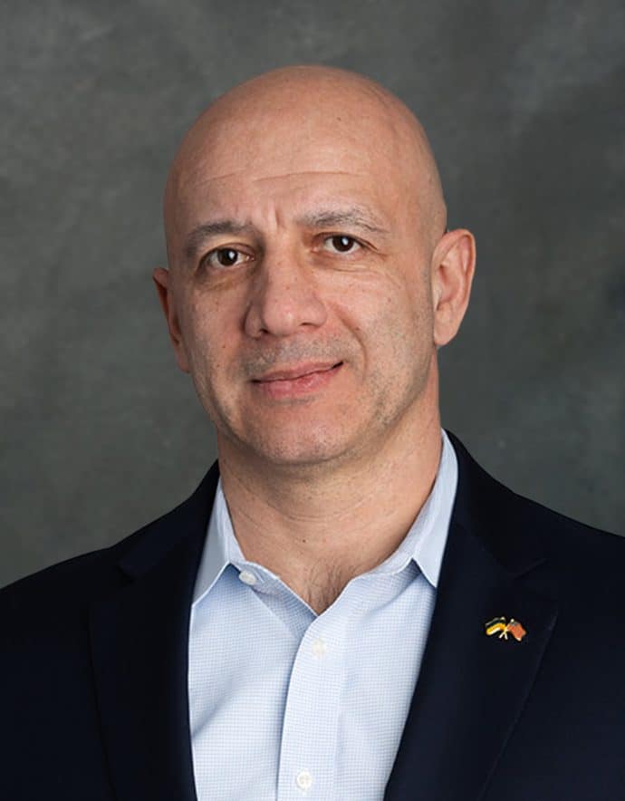 Photo of a man wearing suite with American and Ukrainian flags.